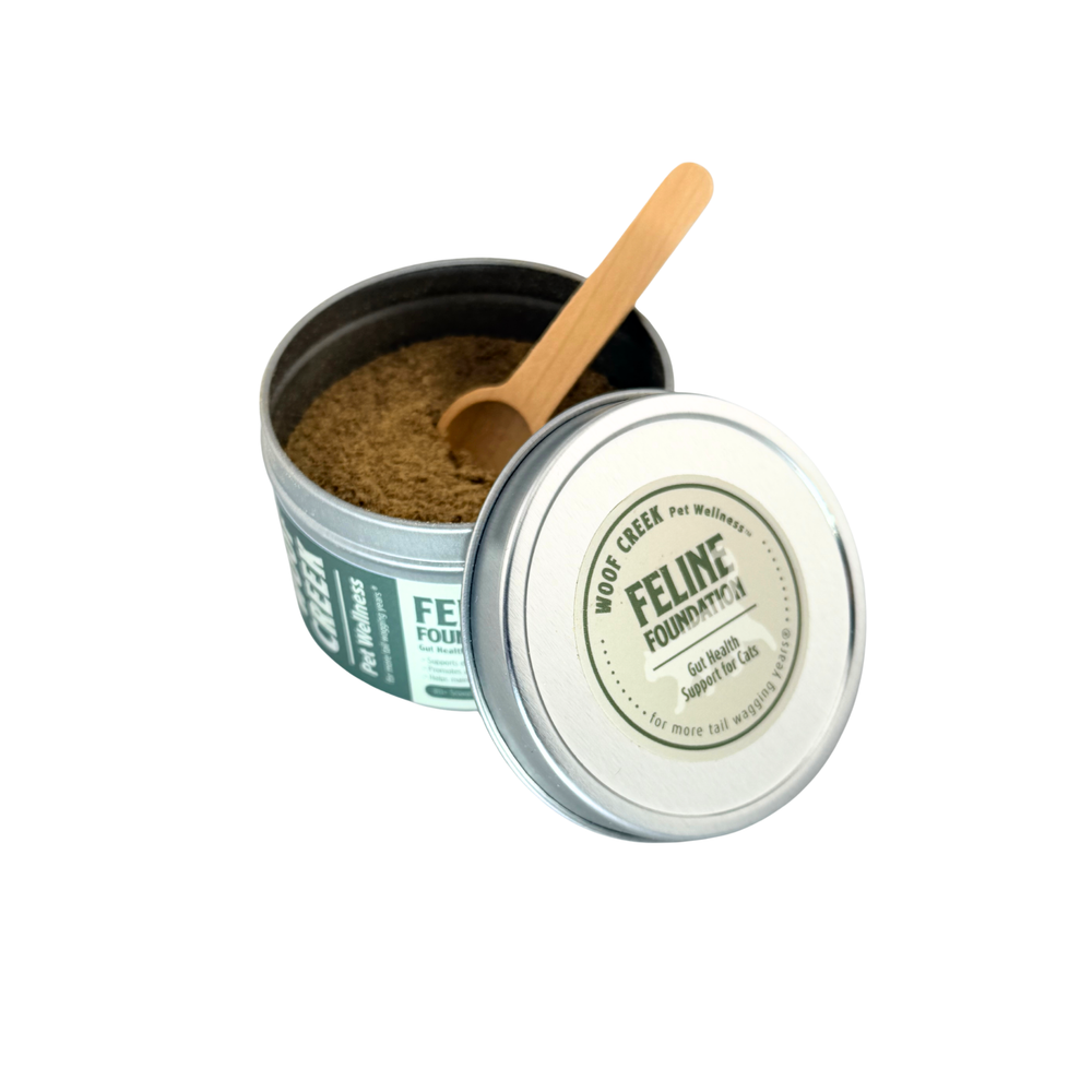 Open tin of Woof Creek Feline Foundation with a wooden scoop resting in the powder