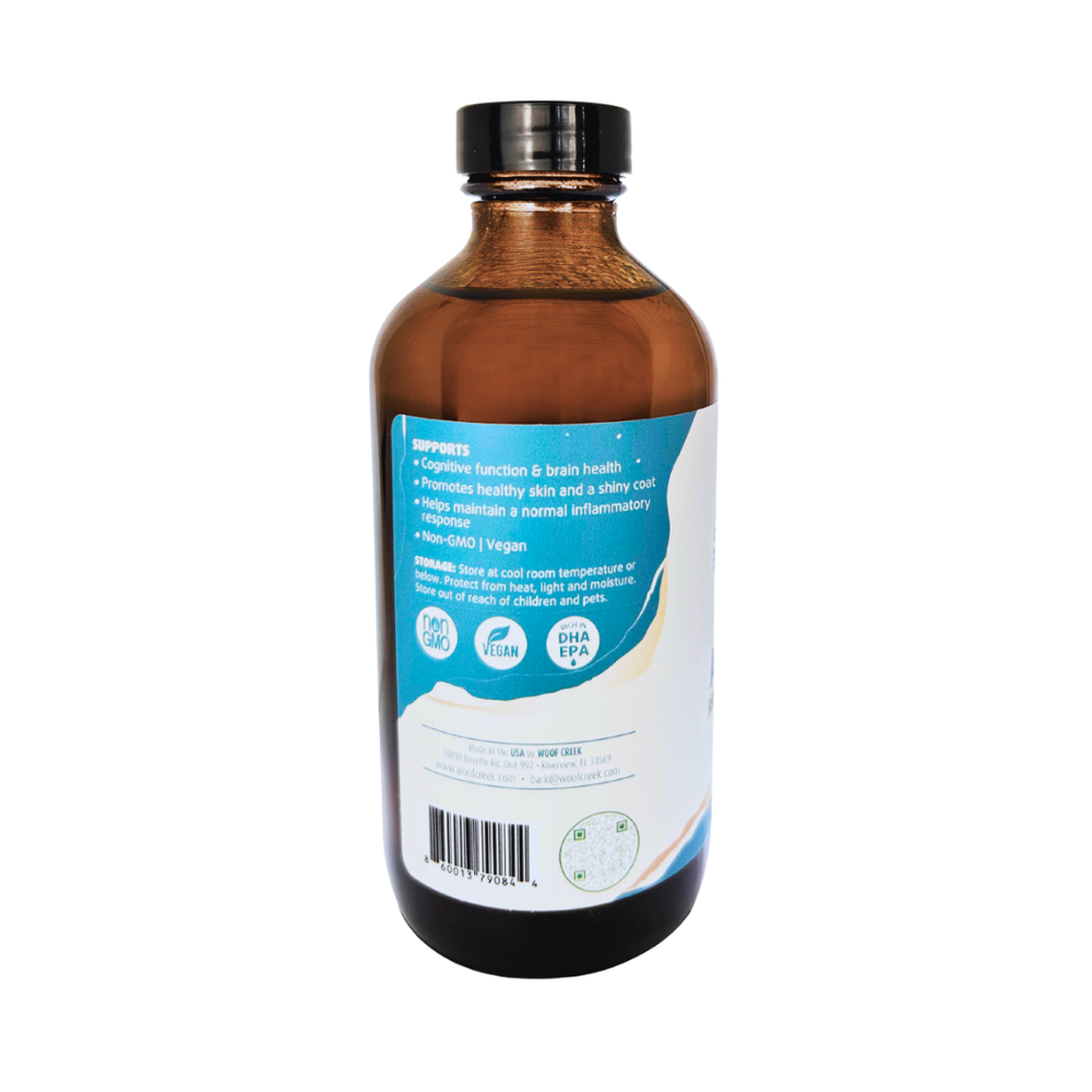 Glass bottle of Woof Creek Pet Wellness Algal Omega-3 plant-based oil for dogs and cats, 8 oz, in a clear glass container.