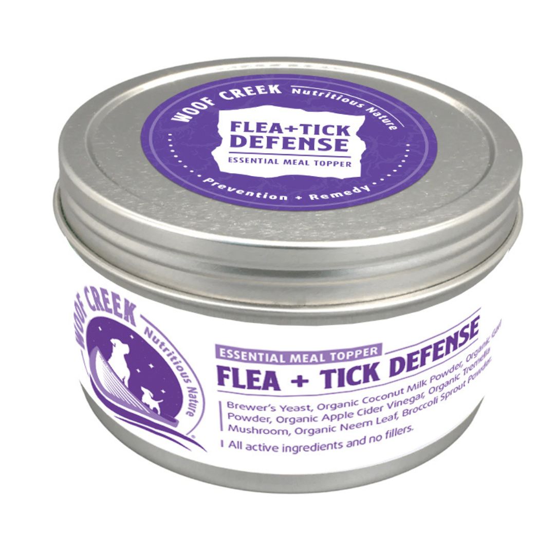 Woof Creek Flea + Tick Defense Essential Meal Topper for pets in a silver tin.